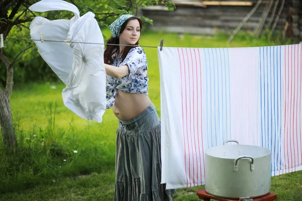 洗浄乾燥のロープに洋服をかけられる妊娠中の女性 — ストック写真