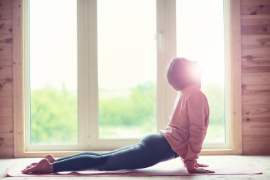 Kız windo önünde halı üzerinde yoga yapan