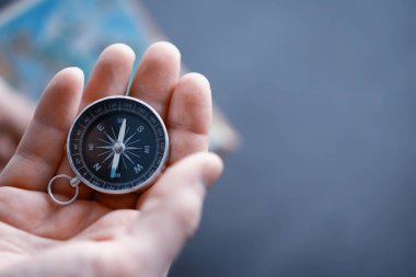 Seyahat konsepti. Elinde manyetik pusula var. El haritasında ve uçak arka planında Retro navigatör. Macera Arkaplanı.