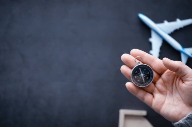 Seyahat konsepti. Elinde manyetik pusula var. El haritasında ve uçak arka planında Retro navigatör. Macera Arkaplanı.