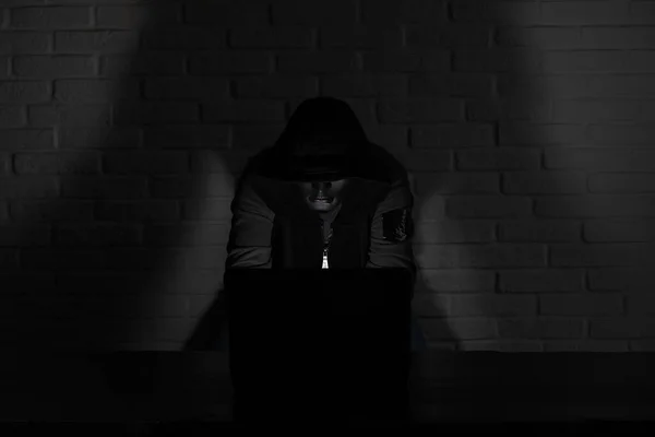 黑客攻击者戴着黑色面具头罩坐在监视器前的桌子上 — 图库照片