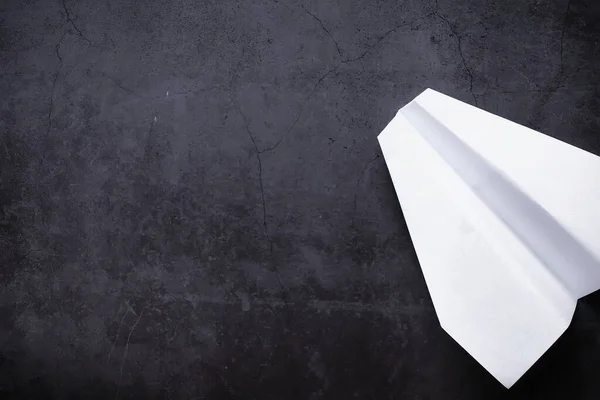 Paper airplane on the table. Origami model on a dark background. Concept. Creative waste time.