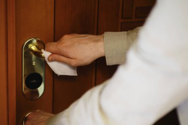 Ev temizliği konsepti. Yüzeylerin tozunu sil. Dezenfektan kapısı TV elektriğini kontrol ediyor. Evdeki karantinada hijyenik tedavi.