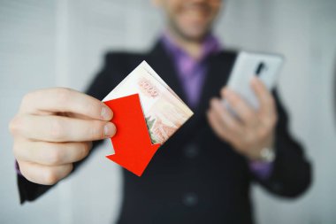 Finansal kriz. Kavram. Elinde para var. Ulusal para biriminin düşüşünün ok sembolü. Rus rublesi ve Amerikan doları arasındaki döviz kuru değişimi..