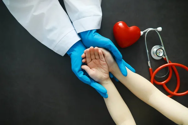 Medical concept. The doctor in gloves holds patient's hand. The moral help of the doctor to his patients. Cardiologist consultation. Epidemic.