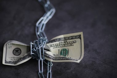 İş konsepti. Ulusal para biriminin değer kaybı. Yüz dolarlık banknot. Enflasyon ve durgunluk. 100 dolarlık banknotu bir ölçü zinciri ile sıkılaştır..