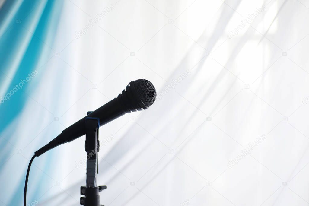 Stand with a microphone. Man holds hands a microphone on tripod. Performance of the artist with a microphone. Scene with a microphone.