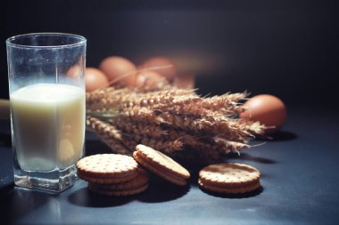 Siyah bir masada buğday ve glüten ile taze çıtır kurabiye. Fırın ve market konsepti. Taze, sağlıklı çavdar ve beyaz kurabiyeler, çuval bezine sütle serpiştirilmiş un. Mısır gevrekli ev yapımı kurabiye..