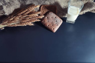 Siyah bir masada buğday ve glüten ile taze somun ekmek. Fırın ve market konsepti. Taze, sağlıklı çavdar ve beyaz somun ekmeği, çuval bezi üzerine serpiştirilmiş un. Tahıllı taze ev yapımı ekmek..