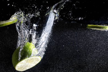 Olgun tatlı limonun üzerine su damlıyor. Metnin için kopyalama alanı olan taze kireç arkaplanı. Vejetaryen ve vejetaryen kavramı.