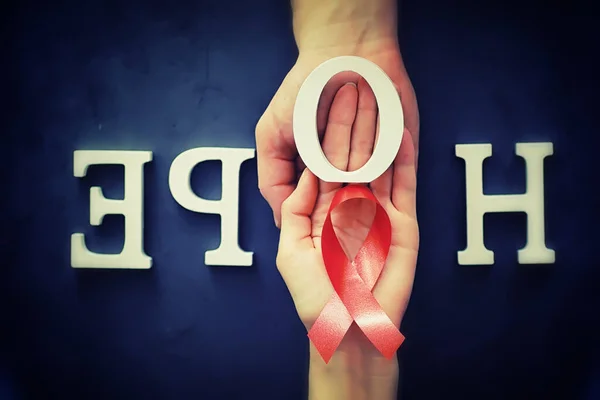 Symbol of human immunodeficiency virus disease. Red ribbon. A helping hand and support. Background.