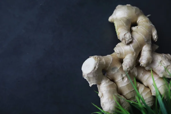 Ginger root whole and sliced. Ginger tea with lemon on the dark background. Fresh ginger root on stone background. Vitamins. Top view. Free space for your text.