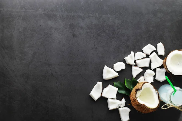 Hindistan cevizi koyu taş bir masada. Hindistan cevizi yağı ve cips.