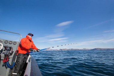 bir olta onun elinde olan adam. Kırmızı ceket. Spor gözlükleri.