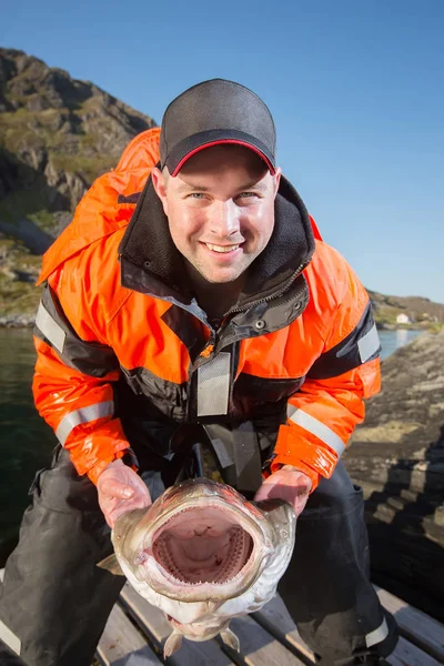 Glücklicher Mann Fischer hält die Fischkiemen riesigen Kabeljau. aufrecht — Stockfoto