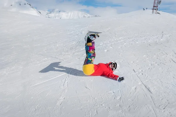 Glad flicka snowboardåkare ligger på snön med armarna utsträckta. — Stockfoto