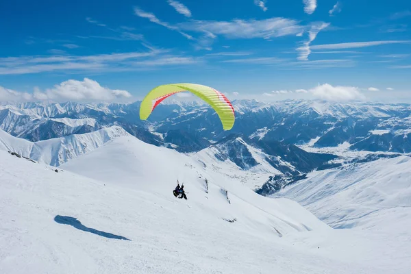 Paraglider flyger mellan de taggiga snöiga topparna — Stockfoto