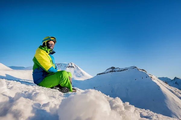 Flicka resenär i ski kostym sitter i snön mot backgro — Stockfoto