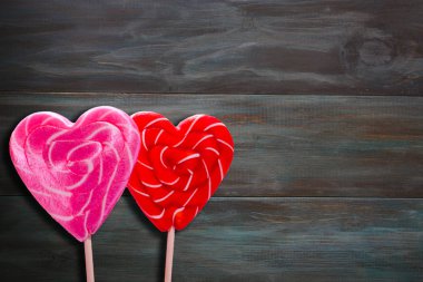 İki lolipop. Kırmızı ve pembe kalpler. - Şeker. Aşk konsepti Sevgililer Günü, evlilik yıldönümü. Yazıtlar için alanı kopyala. koyu arkaplan