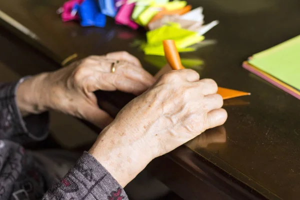 Mãos de senhora sênior dobrar o papel Origami — Fotografia de Stock