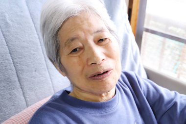 Kıdemli bayan hemşirelik yatağında oturuyor, gülümseyerek.