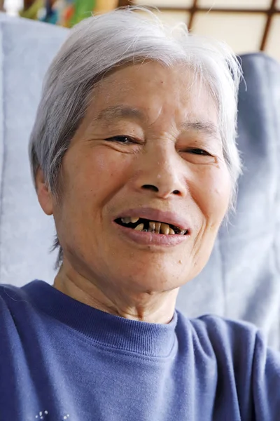 Старшая леди, сидящая на кровати с улыбкой на лице — стоковое фото