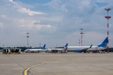Havaalanı otoparkında düşük maliyetli uçaklardan iniyorum. Havaalanı aktarma otobüsleri yolcuları terminale götürüyor.