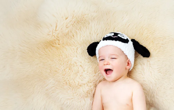 Bebé de un año acostado en un sombrero de oveja sobre lana de cordero —  Fotos de Stock