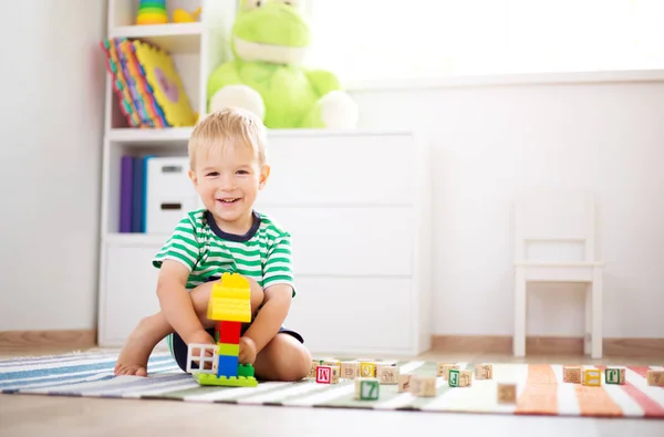 Twee jaar oud kind zittend op de vloer met houten kubussen — Stockfoto