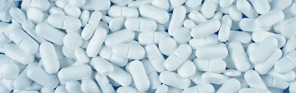 White pills spilled on blue wooden background — Stock Photo, Image