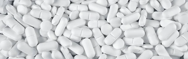 Białe tabletki rozlane na niebieskim drewnianym tle — Zdjęcie stockowe
