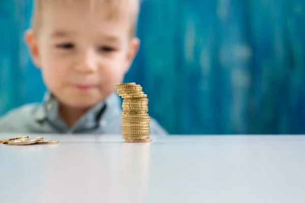 Niño de tres años sentado st la mesa con monedas de dinero —  Fotos de Stock