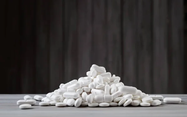 Pastillas blancas derramadas sobre fondo de madera gris — Foto de Stock