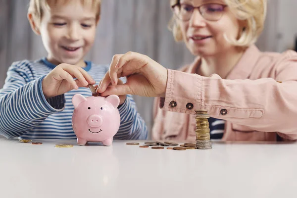 Niño de tres años sentado en la mesa con dinero y una hucha —  Fotos de Stock