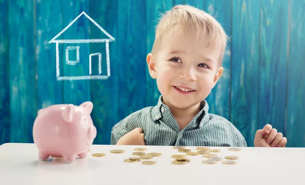 Dreijähriges Kind sitzt mit Geld und Sparschwein am Tisch — Stockfoto