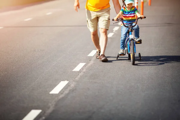 Dziecko na rowerze w kasku z ojcem na asfaltowej drodze — Zdjęcie stockowe