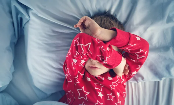 Anak yang mengantuk berbaring di tempat tidur dengan kasur biru — Stok Foto