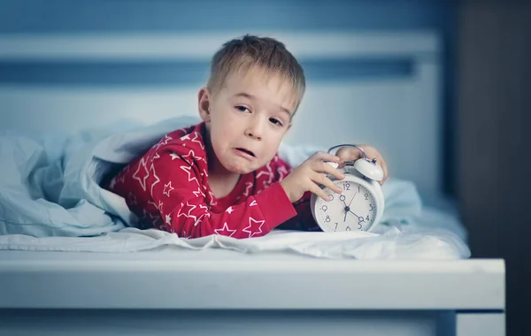 Slaperige jongen liggend in bed met blauw beddengoed — Stockfoto