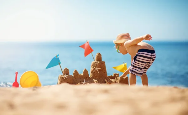 Pojke bygga ett sandslott på stranden på sommaren — Stockfoto