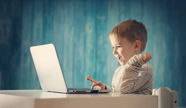 Heureux enfant de cinq ans assis avec un ordinateur portable à la table — Photo