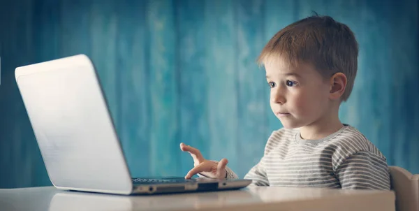 Щаслива п'ятирічна дитина сидить з ноутбуком за столом — стокове фото