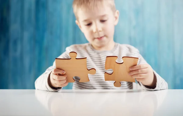 Kleines Kind hält Puzzleteile in der Hand und versucht, sie zu lösen — Stockfoto