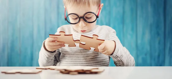 Pequeño niño sosteniendo piezas del rompecabezas y tratando de resolverlo —  Fotos de Stock