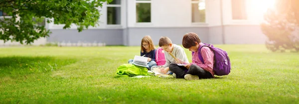 Copii cu rucsaci stând în parc lângă școală — Fotografie, imagine de stoc