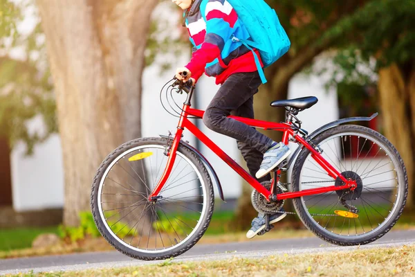 Kind mit Rucksack auf Fahrrad im Park in der Nähe der Schule unterwegs — Stockfoto