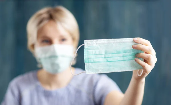Jeune femme en masque médical de protection du visage à l'intérieur sur fond bleu — Photo