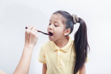 Anne beyaz arka planda kaşıkla kızını besliyor. Çocuk yemek konsepti yiyor..