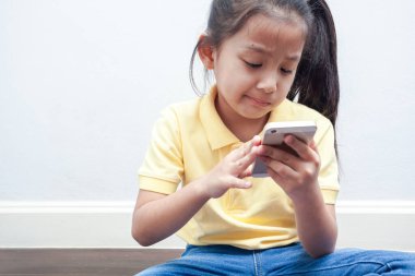 Akıllı telefon kullanan ciddi bir kız. Çocuk teknolojisi ve iletişim konsepti.