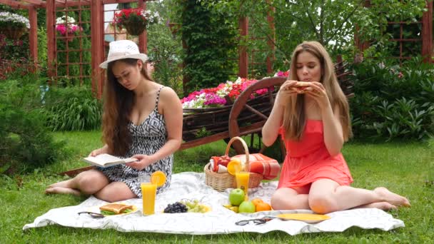 女孩一次野餐，边吃边看一本书 — 图库视频影像