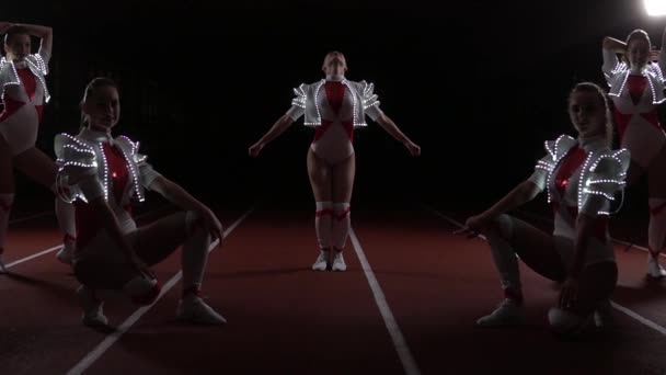 Cheerleaders equipe de pé síncrona em trajes luminosos — Vídeo de Stock